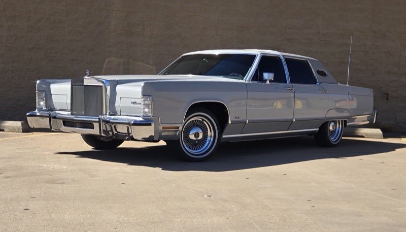 A clean silver 1970s Lincoln Continental parked outside the shop